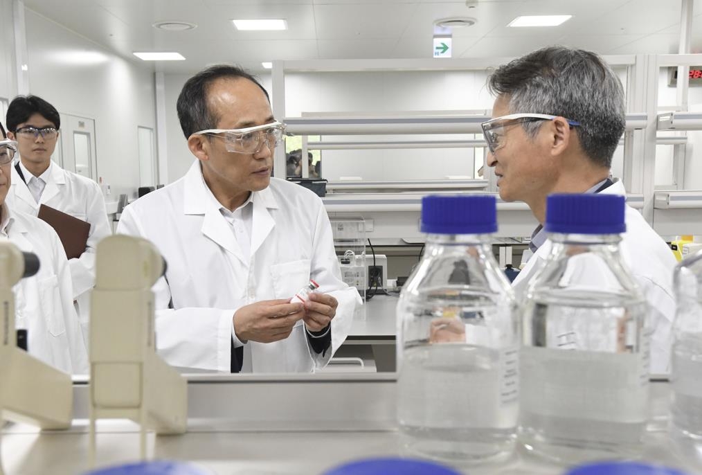 Finance Minister Choo Kyung-ho (L) looks around the production line of Aprogen Inc. in Osong, 108 kilometers south of Seoul, on May 24, 2023, in this photo released by the Ministry of Economy and Finance. (PHOTO NOT FOR SALE) (Yonhap)