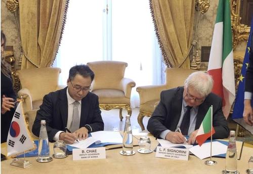 In this photo provided by the Bank of Korea (BOK), BOK Deputy Gov. Chae Byung-deuk (L) and Bank of Italy Vice Gov. Luigi Federico Signorini sign a memorandum of understanding on IT and settlement system cooperation in Rome, Italy, on Dec. 4, 2013. (Yonhap)
