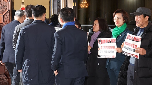 Lawmakers of the minor Justice Party and labor circle protest as lawmakers of the main opposition Democratic Party enter for a party meeting at the National Assembly on Feb. 1, 2024. (Yonhap) 