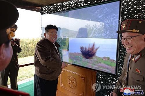 El líder norcoreano Kim Jong-un (centro) se ríe mientras observa el lanzamiento de prueba de proyectiles controlables para un nuevo lanzacohetes múltiple de 240 mm, en esta fotografía de archivo publicada por la Agencia Central de Noticias de Corea del Norte el 11 de mayo de 2024. (Solo para uso en la República de Corea. Sin redistribución) (Yonhap)