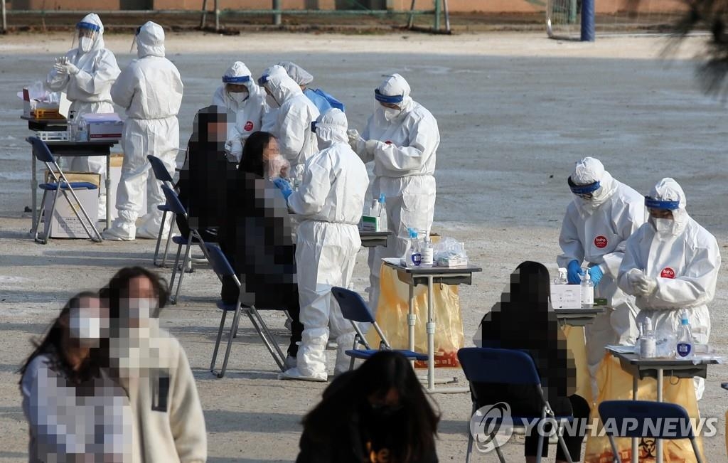 Des travailleurs sanitaires effectuent des tests de dépistage pour le nouveau coronavirus (Covid-19) sur des élèves, dans un centre provisoire installé dans un collège à Gwangju, dans le sud-ouest du pays le lundi 30 novembre 2020.
