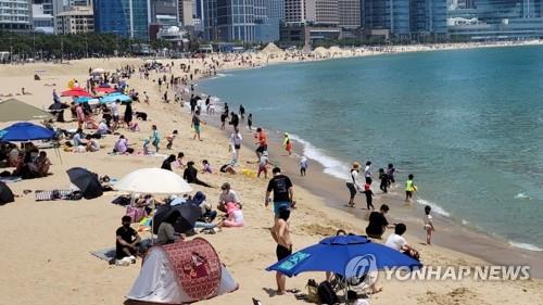 Des personnes se détendent sur la plage Haeundae à Busan le dimanche 30 mai 2021. 