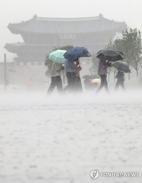 Des gens traversent la place Gwanghwamun sous la pluie dans le centre de Séoul, le 8 août 2022.