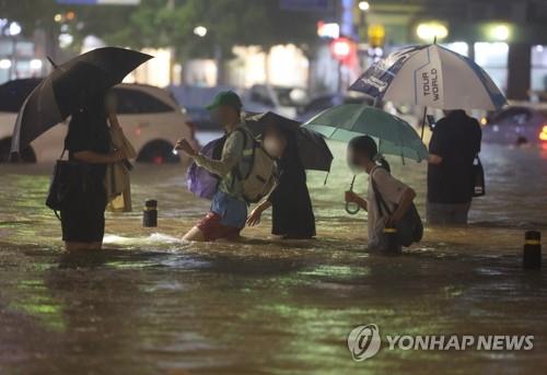 Des gens pataugent le 8 août 2022 dans une rue inondée dans le sud de Séoul alors que plus de 100 mm de pluies par heure se sont abattues sur Séoul et dans ses environs, un record en 80 ans.