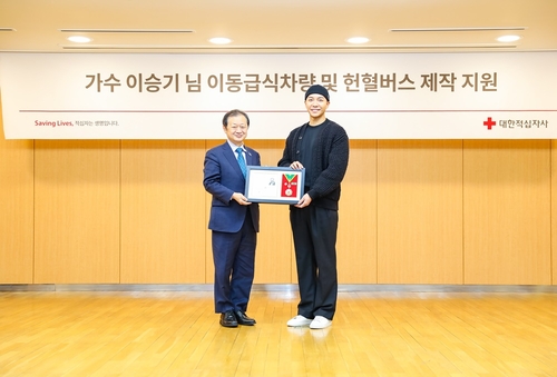 Le chanteur Lee Seung-gi (à dr.) et Shin Hee-young, chef de la Croix-Rouge sud-coréenne, posent pour une photo lors de la cérémonie tenue à l'occasion du don de Lee de 550 millions de wons, au bureau de l'organisation à Séoul le 13 janvier 2023. (Photo fournie par l'organisation humanitaire. Revente et archivage interdits)