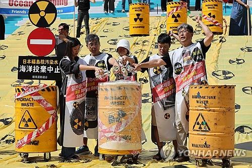 ソウル市内の世宗文化会館前で行った記者会見で、日本製ビールを捨てるパフォーマンスを行う市民団体のメンバー＝１８日、ソウル（聯合ニュース）