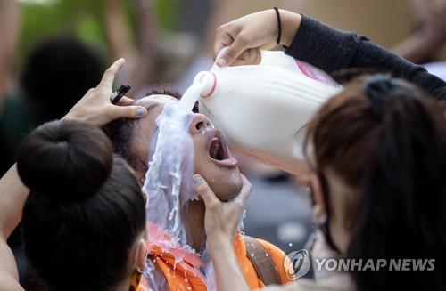 최루탄 가스에 노출된 한 미국 시민의 얼굴에 우유를 뿌리는 모습