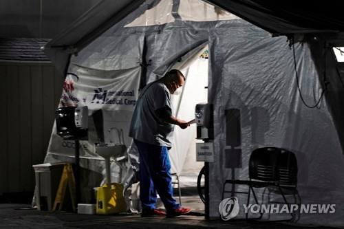 미 캘리포니아 헌팅턴파크 지역병원의 응급실 밖에 마련된 텐트에 있는 환자를 의료진이 점검하고 있다. [로이터=연합뉴스 자료사진]