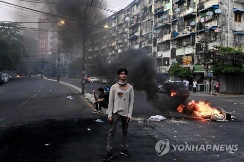 양곤 시내에서 한 시위 참여자가 불타는 바리케이드 옆에 서있다. 2021.3.30 [AFP=연합뉴스]