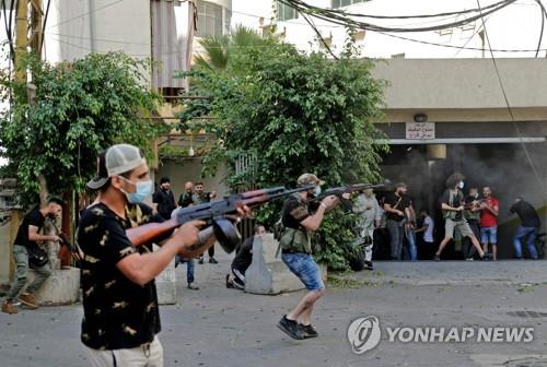 14일 레바논 수도 베이루트 남부의 타유네에서 시위대를 겨냥한 총격이 발생한 가운데, 헤즈볼라 대원들이 소총을 들고 응사하고 있다.[AFP=연합뉴스]