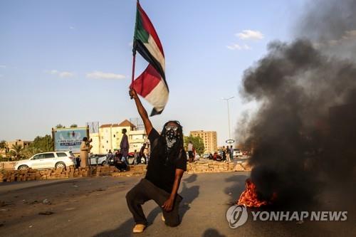 수단 수도 하르툼에서 열린 반군부 시위 도중 국기를 치켜든 남성.