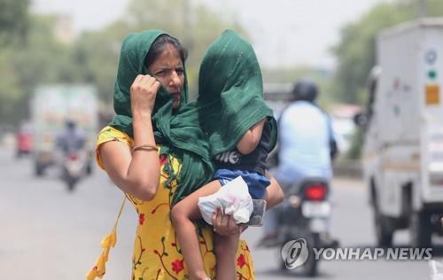  더위를 피하고자 안은 아이를 천으로 감싼 채 이동하는 인도 여성
