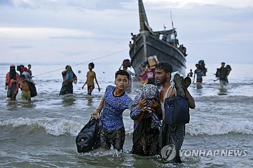 로힝야족 난민 인도네시아 상륙  지난해 11월 16일 인도네시아 아체주의 한 바닷가에서 미얀마 로힝야족 난민들이 배에서 내려 해안가로 걸어오고 있다. / AP 연합뉴스