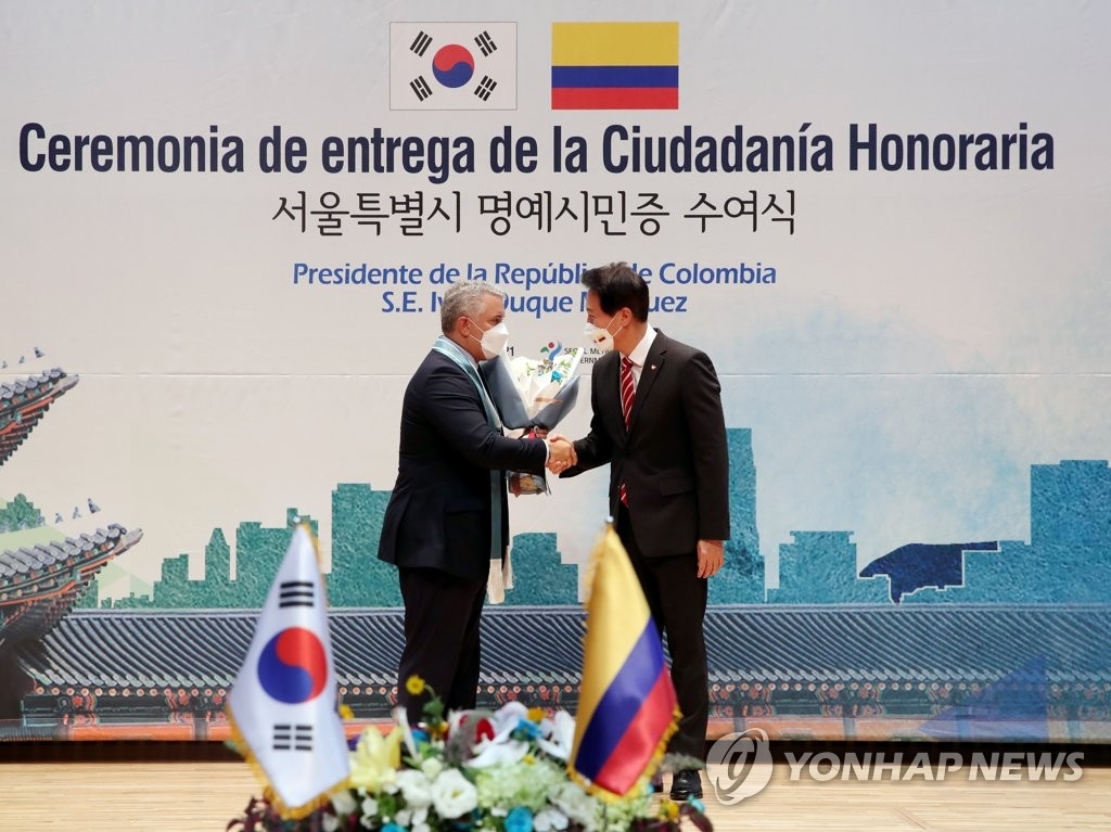 El alcalde de Seúl, Oh Se-hoon (dcha.), estrecha la mano del presidente colombiano, Iván Duque Márquez, tras otorgarle el certificado de ciudadanía honoraria, el 26 de agosto de 2021, en el Ayuntamiento de Seúl. 