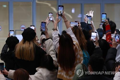 Un grupo de fanes toma fotos de integrantes de BTS que van llegando al Aeropuerto Internacional de Incheon, al oeste de Seúl, el 6 de diciembre de 2021, tras un viaje a EE. UU. para una serie de conciertos del septeto en Los Ángeles.