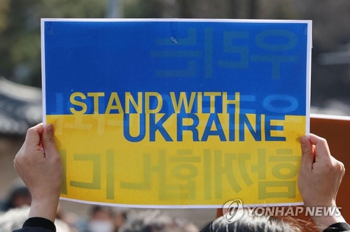 En la imagen de archivo, tomada el 8 de marzo de 2022, se muestra a una persona sosteniendo un cartel que dice "Stand with Ukraine" (Apoyamos a Ucrania), durante una manifestación de un grupo de feministas en Seúl, para expresar su objeción a la invasión rusa a Ucrania, como parte de las actividades para conmemorar el Día Internacional de la Mujer.