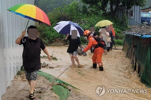 La foto, proporcionada, el 30 de junio de 2022, por las autoridades contra incendios de la provincia de Gyeonggi, muestra a residentes evacuando con la ayuda de los bomberos, en Yangju, provincia de Gyeonggi. (Prohibida su reventa y archivo)