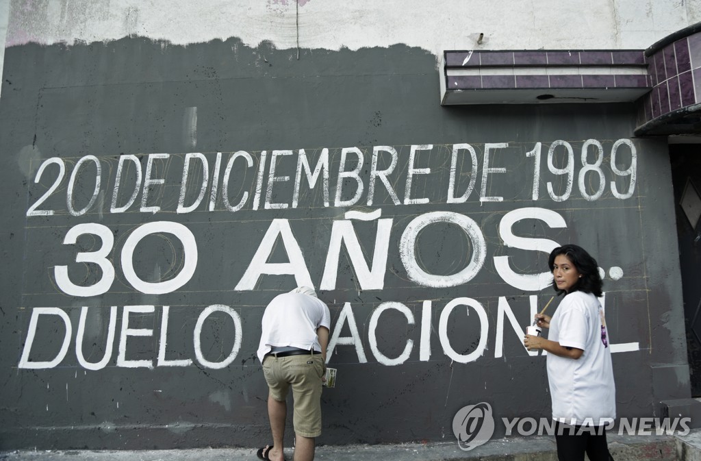 벽에 파나마 침공 30주년을 기리는 메시지를 적고 있는 시민