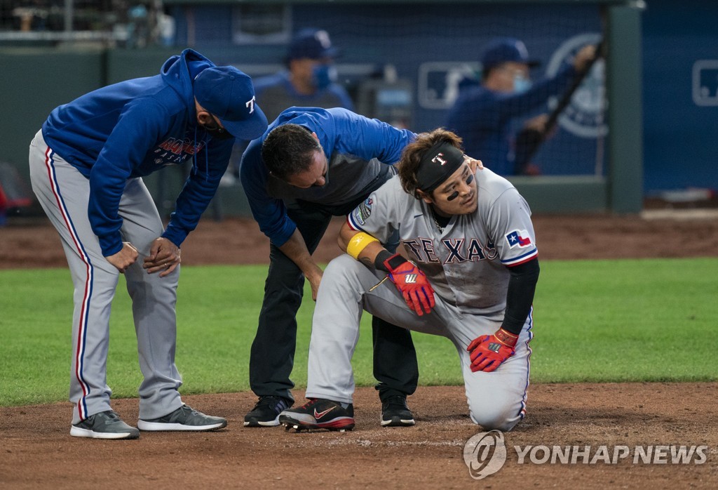 In this Associated Press photo, Choo Shin-soo of the Texas Rangers (R) is checked by a team trainer after spraining his right wrist on a slide during the top of the fourth inning of a Major League Baseball regular season game against the Seattle Mariners at T-Mobile Park in Seattle on Sept. 7, 2020. (Yonhap) 