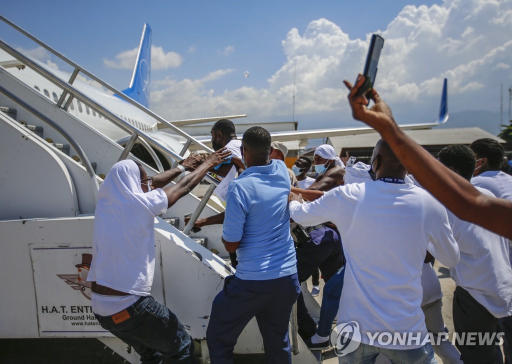 21일(현지시간) 미국서 추방돼 아이티 공항에 도착한 이민자들이 미국행 비행기에 도로 오르려고 달려들고 있다.