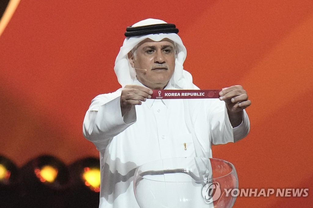 In this Associated Press photo, former Qatari football international Adel Ahmed MalAllah holds up the name of South Korea during the 2022 FIFA World Cup draw at the Doha Exhibition and Convention Center in Doha on April 1, 2022. (Yonhap)