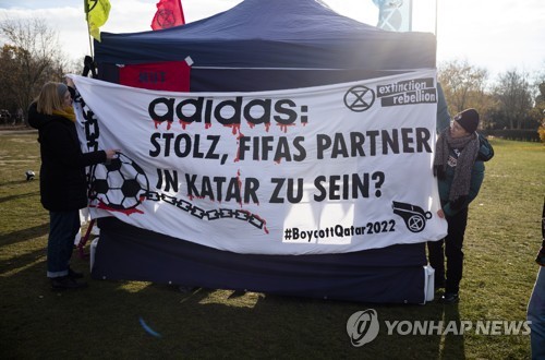 지난 19일 독일 베를린에서 카타르 월드컵을 반대하는 시위대가 아디다스의 월드컵 후원을 비판하는 현수막을 설치하는 모습 