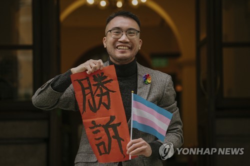 (AP=연합뉴스) 홍콩 트랜스젠더 활동가 헨리 에드워드 쯔가 지난 6일 홍콩 법원의 판결을 환영하며 '승소'라고 적힌 종이를 들어 보인 모습. 2023.2.7.