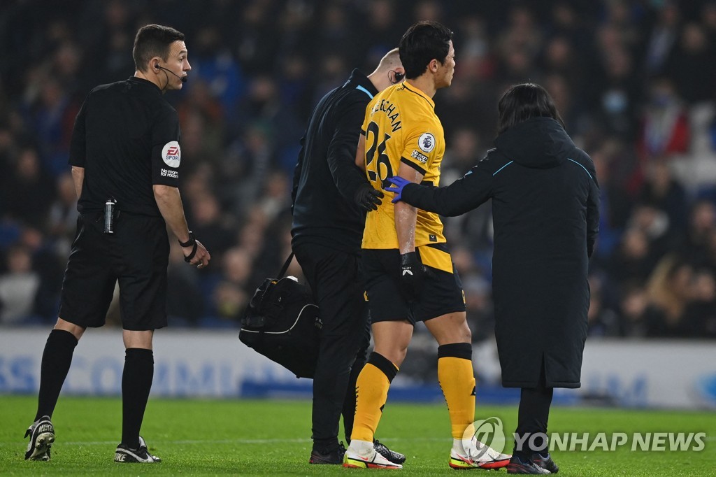 In this AFP file photo from Dec. 15, 2021, Hwang Hee-chan of Wolverhampton Wanderers (2nd from R) is helped off the pitch by a team trainer after picking up a hamstring injury during a Premier League match against Brighton & Hove Albion at American Express Community Stadium in Brighton, England. (Yonhap)