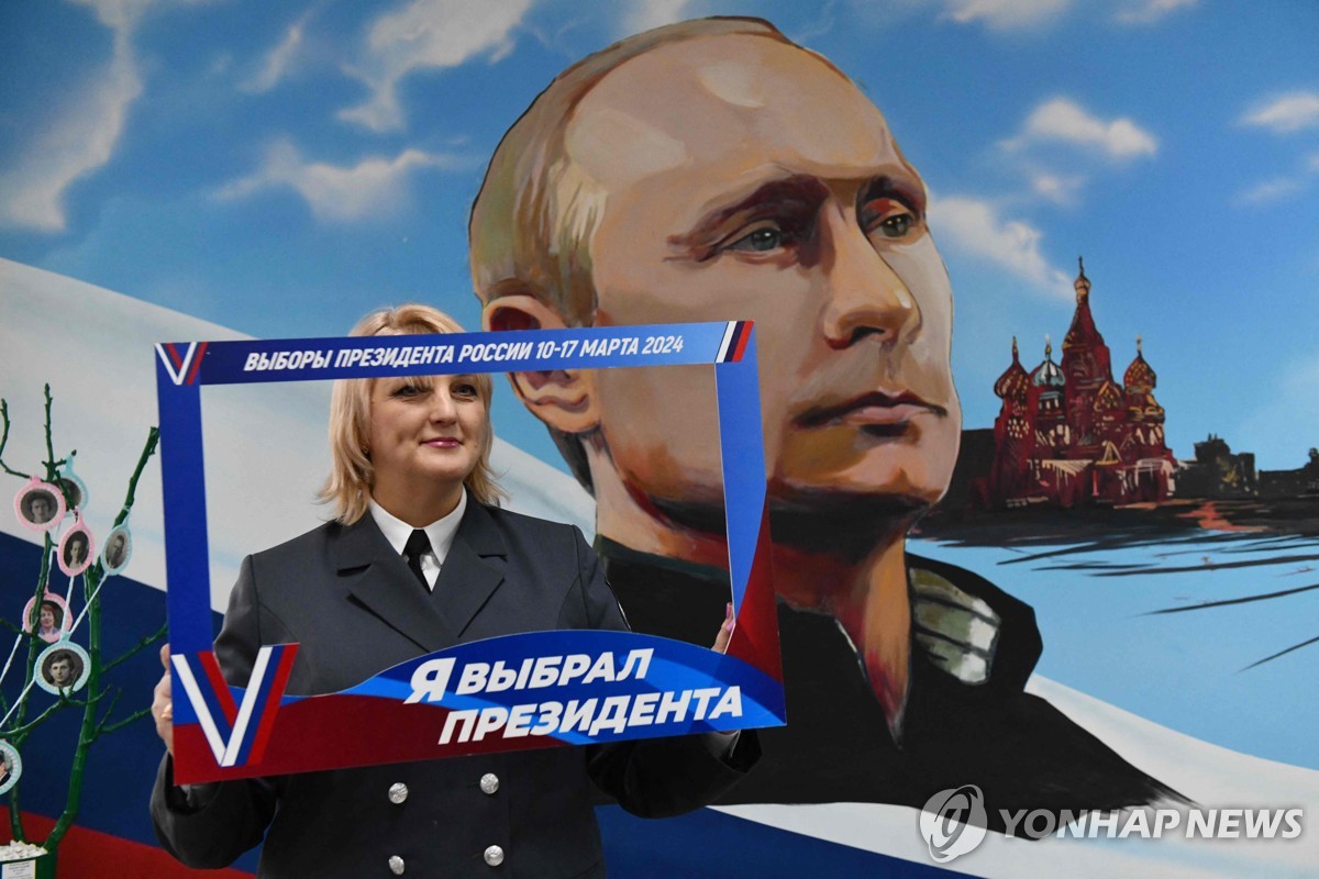 블라디미르 푸틴 러시아 대통령이 그려진 벽화 앞에서 기념 촬영을 하는 러시아 여성