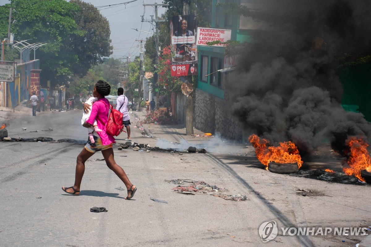 (포르토프랭스 AFP=연합뉴스) 20일(현지시간) 아이티 수도 포르토프랭스에서 한 여성이 아이를 안고 가고 있다. 2024.3.20 photo@yna.co.kr