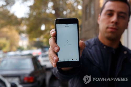 인터넷 접속이 차단된 휴대전화 화면을 보여주는 이란 남성