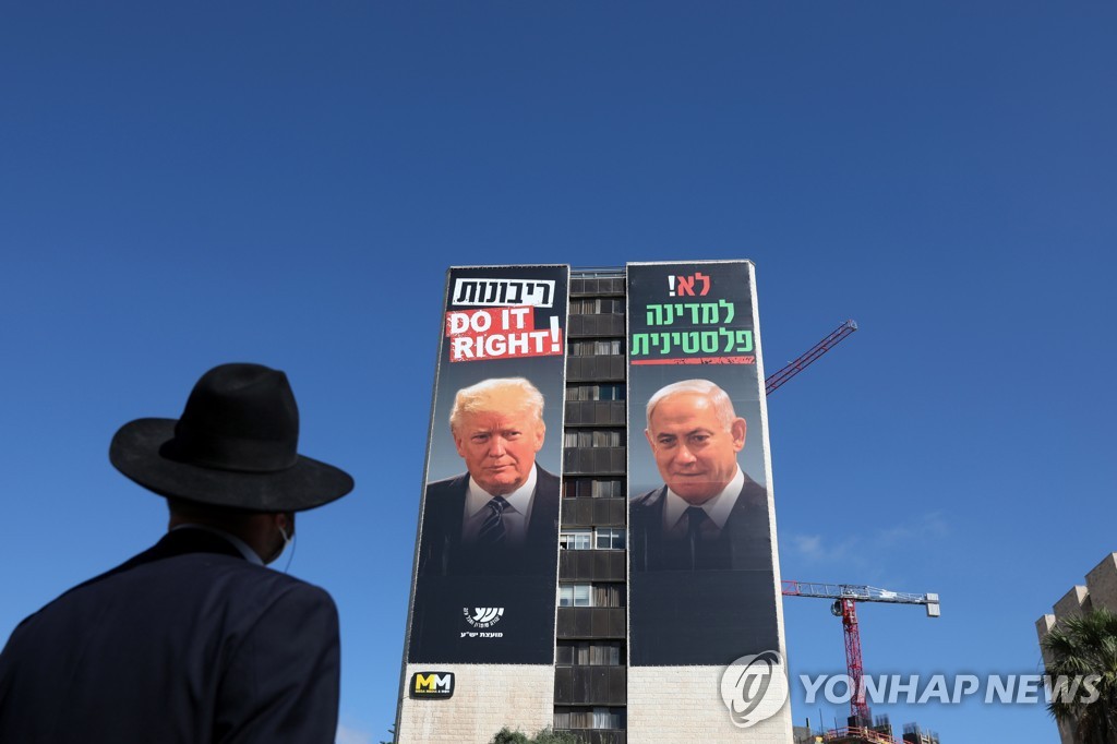 트럼프 대통령과 네타냐후 이스라엘 총리가 나란히 있는 광고 지켜보는 예루살렘의 초정통파 유대교인