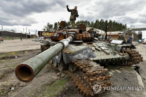 파괴된 러시아 탱크를 살펴보는 우크라이나인