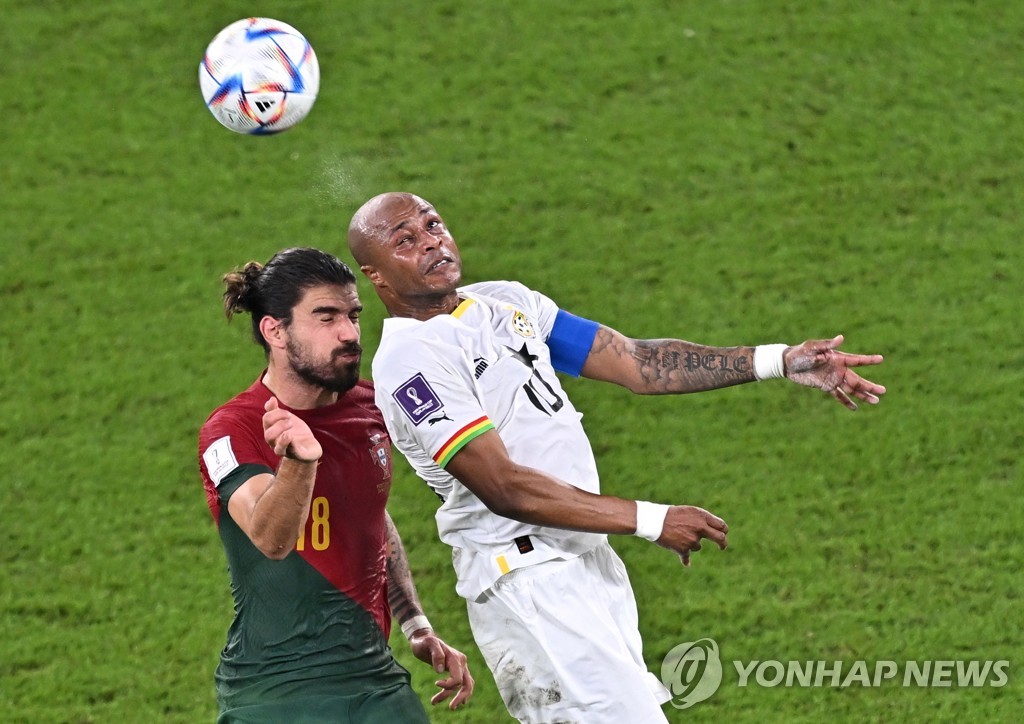 In this EPA photo, Andre Ayew of Ghana (R) battles Joao Cancelo (L) of Portugal for the ball during the teams' Group H match at the FIFA World Cup at Stadium 974 in Doha on Nov. 24, 2022. (Yonhap)