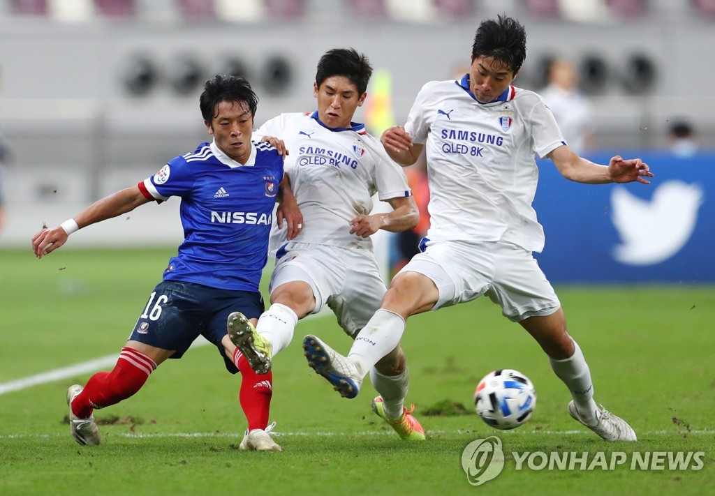 In this Reuters photo, Jang Ho-ik (C) and Han Suk-jong (R) of Suwon Samsung Bluewings are in action against Ryo Takano of Yokohama F. Marinos in the round of 16 at the Asian Football Confederation Champions League at Khalifa International Stadium in Doha on Dec. 7, 2020. (Yonhap)