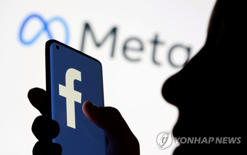 메타 플랫폼 로고를 배경으로 페이스북 로고가 찍힌 스마트폰을 들고 있는 한 여성