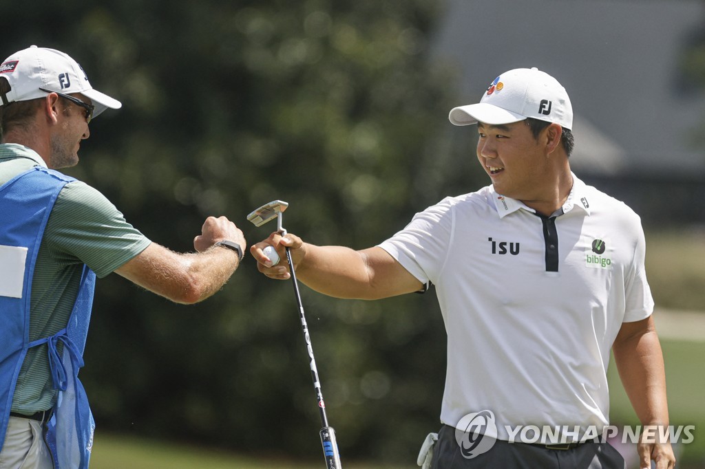 In this USA Today Sports via Reuters, Kim Joo-hyung of South Korea (R) bumps fists with his caddie Jacob Fleck after making a birdie on the eighth hole during the final round of the Wyndham Championship at Sedgefield Country Club in Greensboro, North Carolina, on Aug. 7, 2022. (Yonhap)