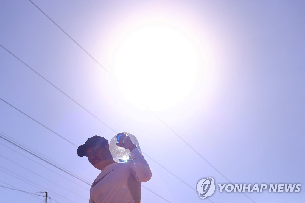 폭염 속 물통을 이고 가는 남성