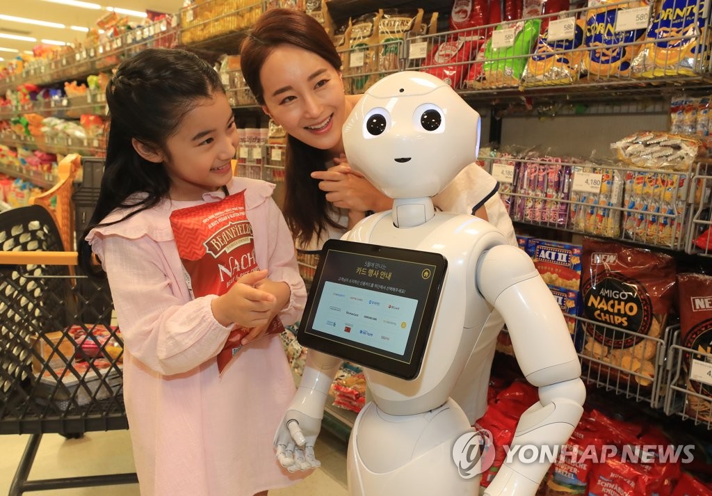 In this file photo taken on May 9, 2018, models pose with E-Mart Inc.'s robot concierge, dubbed Pepper, at one of its discount stores in Seoul. (Yonhap) 