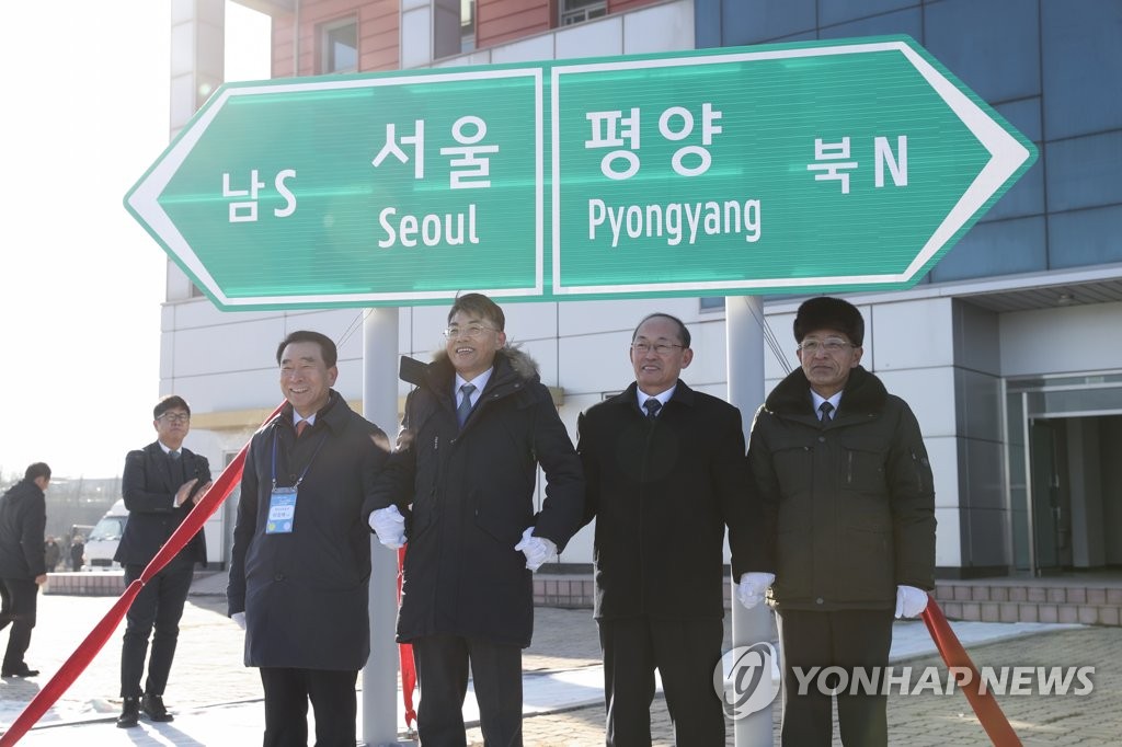 South and North Koreans pose for a photo in front of a sign board the two Koreas unveiled as part of the groundbreaking ceremony for an inter-Korean railway and road project on Dec. 26, 2018. (Yonhap) 