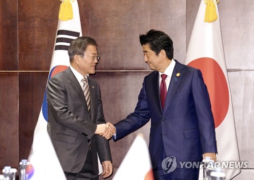 握手を交わす文大統領（左）と日本の安倍晋三首相（資料写真）＝（聯合ニュース）