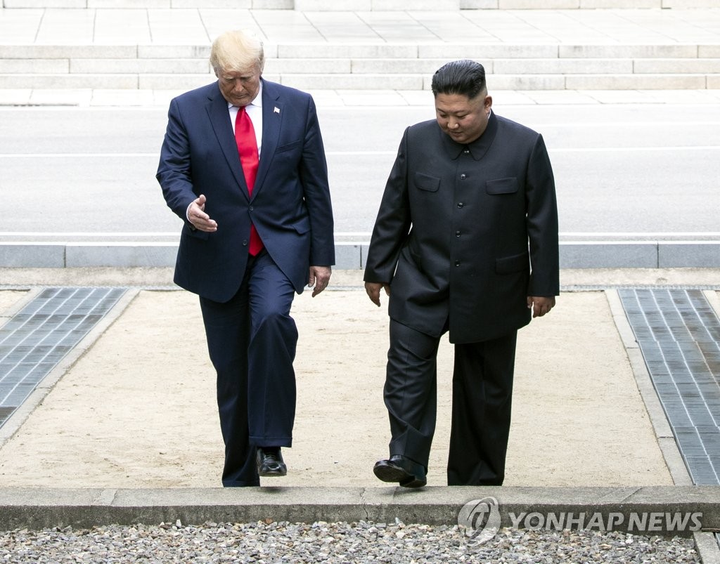 In the file photo, taken June 30, 2019, U.S. President Donald Trump (L) and North Korean leader Kim Jong-un are seen about to cross over to the South Korean side of the Military Demarcation Line after holding a brief meeting on the North Korean side of the line that divides the two Koreas. The historic meeting in North Korea, technically, marked the third encounter between the two leaders that followed their bilateral summits in June 2018 and February 2019. (Yonhap)