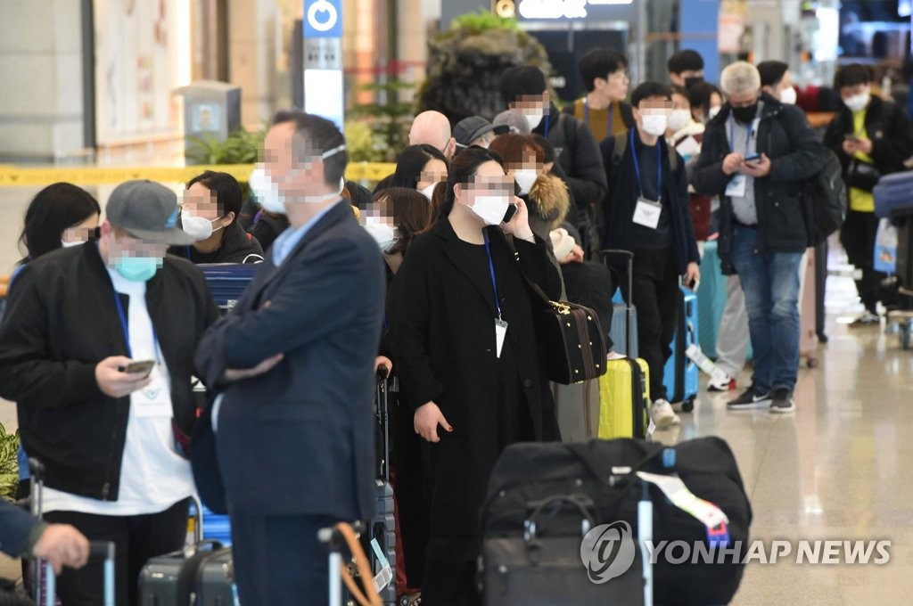 Arrivals from Germany wait to be transported to a coronavirus testing station at Incheon International Airport, west of Seoul, on March 22, 2020, after South Korea toughened quarantine measures for arrivals from Europe in order to contain the virus outbreak. (Yonhap)