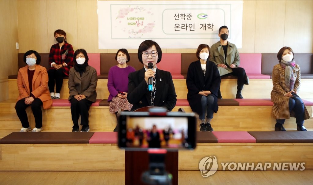 Los maestros de la Escuela de Enseñanza Media Seonhak, en Incheon, al oeste de Seúl, saludan a los estudiantes, el 9 de abril de 2020, en la ceremonia de inicio de cursos emitida en línea. 