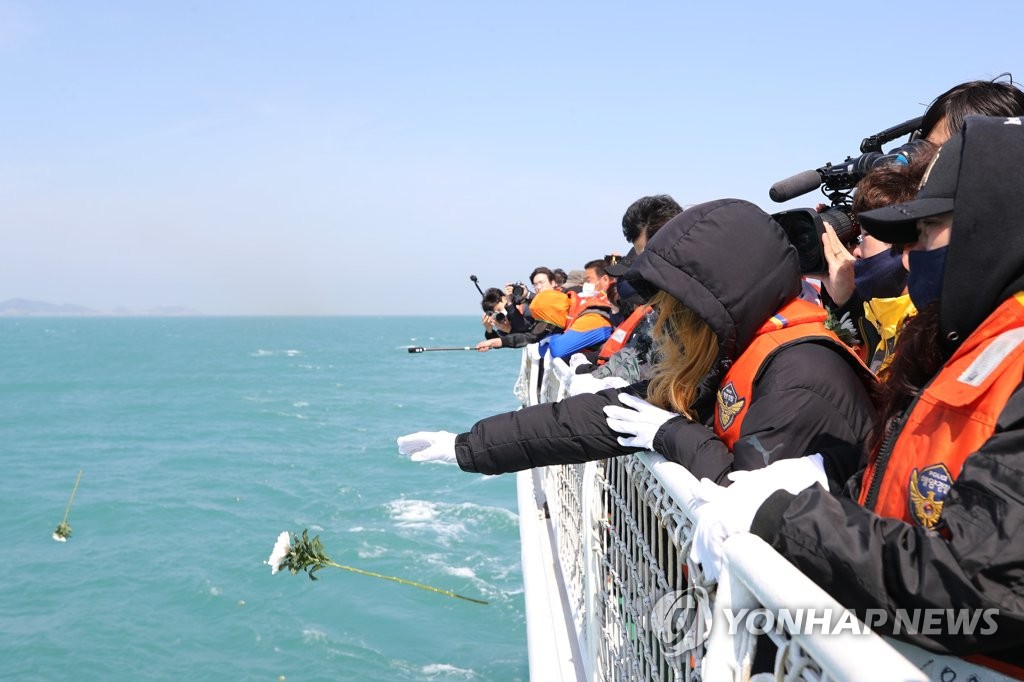 Bereaved families throw flowers into the sea for those killed in a 2014 sinking of a passenger ferry off South Korea's western coast near Jindo Island on April 16, 2020, the sixth anniversary of the sinking of the 6,800-ton Sewol ferry. (Yonhap)