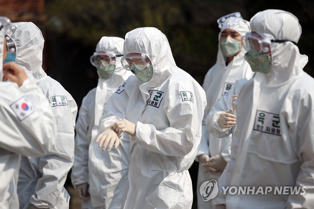 Military health workers clad in protective suits prepare to work at a middle school in Daegu on April 16, 2020. (Yonhap)