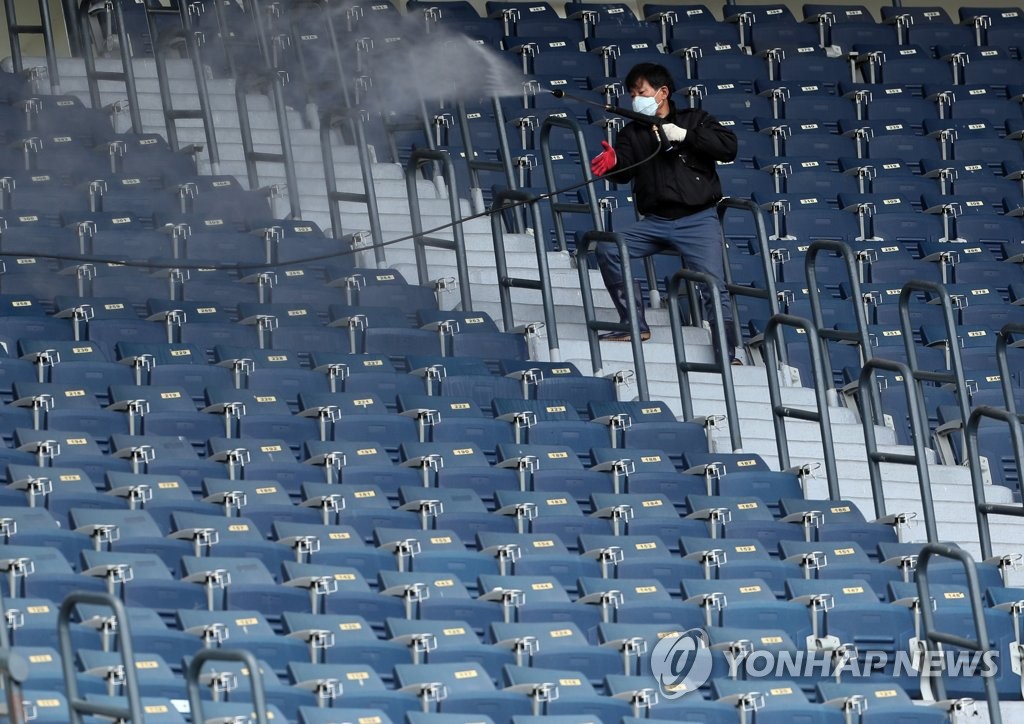 A stadium official disinfects seats at Jamsil Baseball Stadium in Seoul in this photo taken April 24, 2020. (Yonhap)