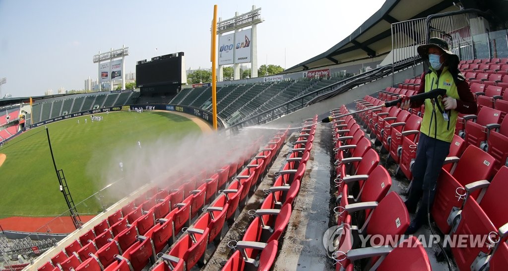 This file photo from May 1, 2020, shows a stadium worker at Jamsil Baseball Stadium in Seoul disinfecting seats ahead of the start of the Korea Baseball Organization regular season. (Yonhap)