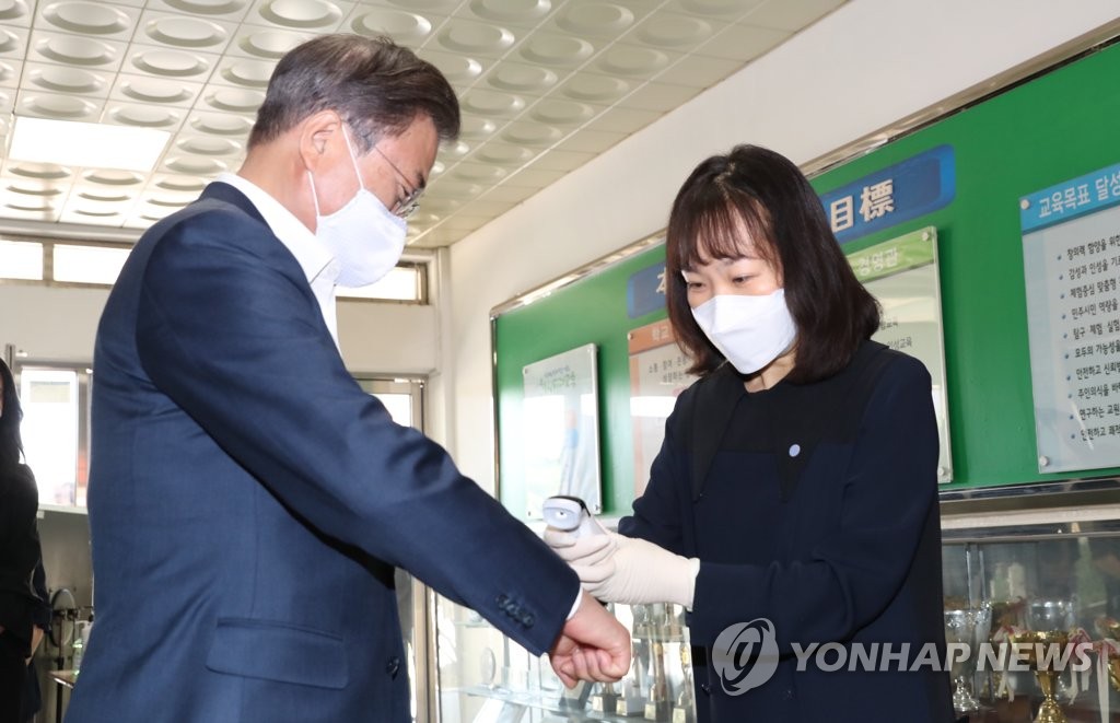 President Moon Jae-in gets his temperature checked at a classroom of Jungkyung High School in Seoul on May 8, 2020. (Yonhap)