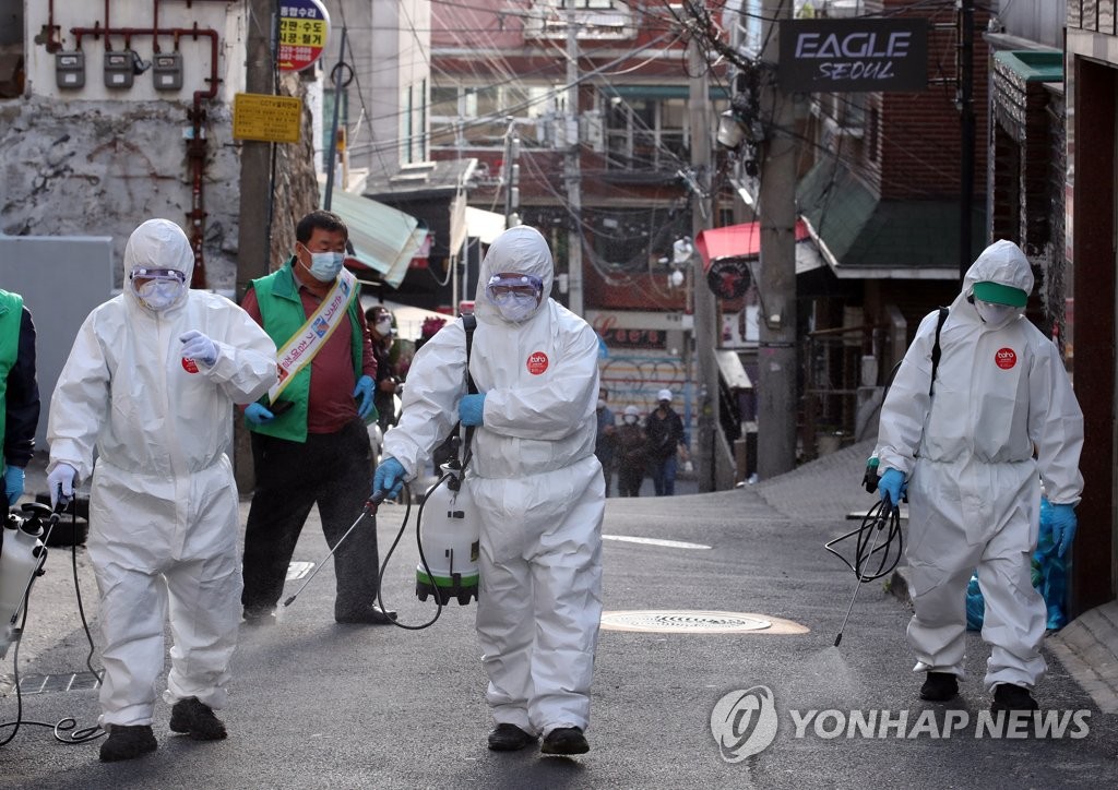 Des bénévoles sanitaires désinfectent une rue d'Itaewon, dans l'arrondissement de Yongsan, le mardi 12 mai 2020. 